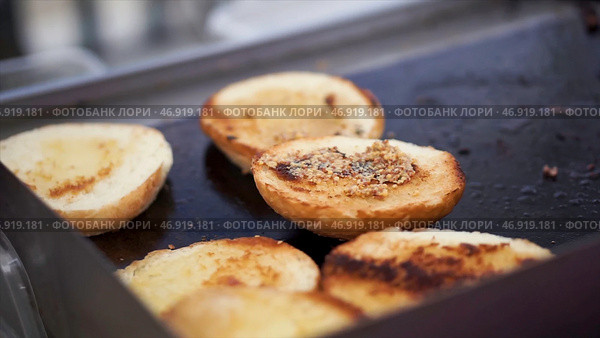 Baking potatoes on the grill, the cook lubricates the potatoes with sauce. Стоковое фото, фотограф David Kashakhi / Фотобанк Лори