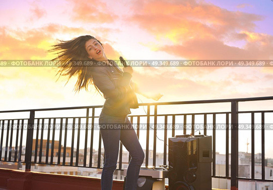 Band girl singing karaoke outdoor at roof terrace . Band girl singing karaoke outdoor at roof terrace in the city. Стоковое фото, агентство Ingram Publishing / Фотобанк Лори