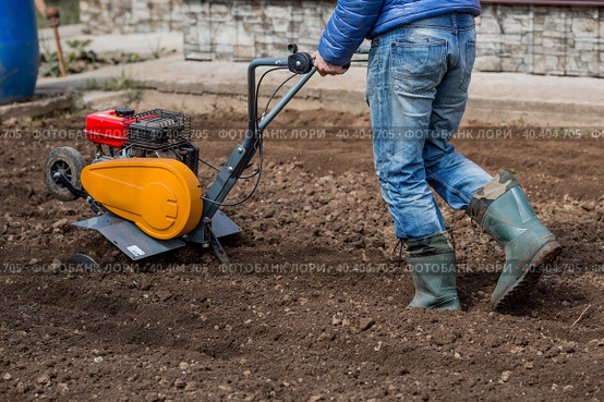 Banner. Man Farmer plows the land with a cultivator. Agricultural machinery: cultivator for tillage in the garden,motor cultivator. Стоковое фото, фотограф Photojuli / Фотобанк Лори