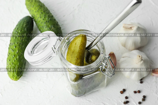 Баночка с вкусными ферментированными огурцами на светлом столе. Стоковое фото, фотограф Pixel_shot / Фотобанк Лори