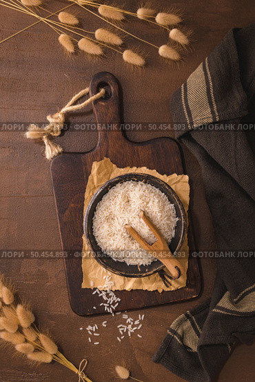 Basmati rice in ceramic bowl with wooden scoop on rustic countertop. Стоковое фото, агентство Ingram Publishing / Фотобанк Лори