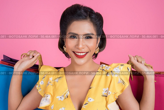Beautiful asian woman holding colored shopping bags. Стоковое фото, агентство Ingram Publishing / Фотобанк Лори