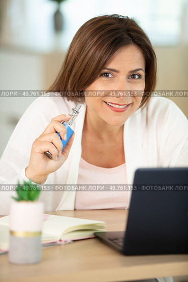 beautiful brunette smoking electronic cigarette and working on her laptop. Стоковое фото, агентство Ingram Publishing / Фотобанк Лори