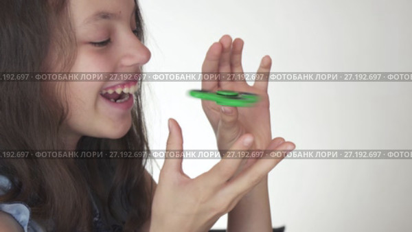Beautiful cheerful teen girl playing with green fidget spinner on white background stock footage video. Стоковое видео, видеограф Юлия Машкова / Фотобанк Лори