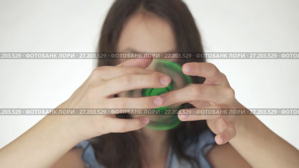 Beautiful cheerful teen girl playing with green fidget spinner on white background stock footage video. Стоковое видео, видеограф Юлия Машкова / Фотобанк Лори