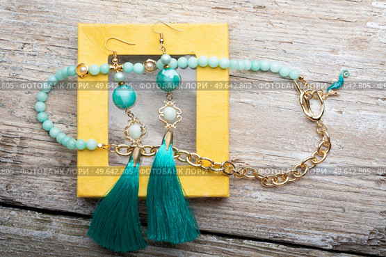 beautiful handmade  turquoise  jewelry with natural gems in yellow box around old style wooden background. close up. fashion concept. Стоковое фото, агентство Ingram Publishing / Фотобанк Лори