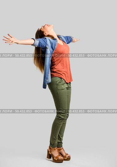 Beautiful happy woman with arms up over a gray background. Стоковое фото, агентство Ingram Publishing / Фотобанк Лори