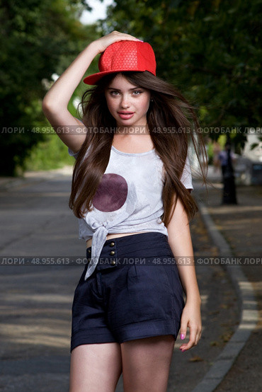 beautiful long haired teen model on pave. red cap, grey t-shirt, dark blue shorts. Стоковое фото, агентство Ingram Publishing / Фотобанк Лори