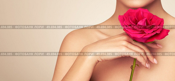 Beautiful model with a rose flower. Perfect woman face makeup close up. Beautiful nails. Perfect skin. Стоковое фото, агентство Ingram Publishing / Фотобанк Лори