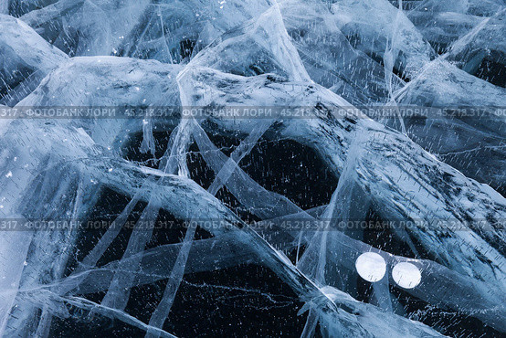 Beautiful natural blue ice texture of surface of frozen Baikal Lake in cold winter day. Nature abstract pattern of white cracks and bubbles. Winter background, mock up, flat lay, blank, close-up, top view. Стоковое фото, фотограф Виктория Катьянова / Фотобанк Лори