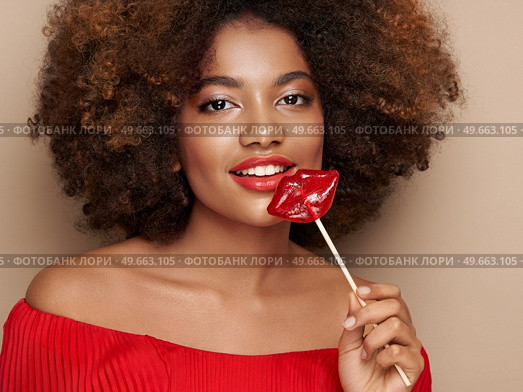 Beautiful portrait of an African girl with a lips shaped lollipop. Valentine’s Day. Symbol of love. Стоковое фото, агентство Ingram Publishing / Фотобанк Лори