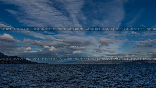 Beautiful seascape. Ripples on the surface of the blue ocean. Mountains and coastline are visible in the distance. Picturesque clouds in the sky. Argentina. The Beagle Channel. Tierra del Fuego. Стоковое фото, фотограф Вера Ивановна Кубарева / Фотобанк Лори