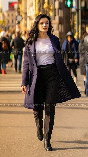 Beautiful serious smart brunette girl walking down street of St. Petersburg in city center. Charming thoughtful woman with long dark hair wanders alone. Стоковое фото, фотограф Natalia Gdovskaia / Фотобанк Лори