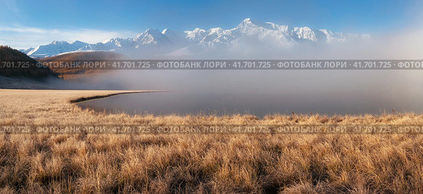 Beautiful sunny foggy morning in the mountains. Autumn frost on dry grass. Snowy peaks. North Chuysky Range and Lake Dzhangyskol. Russia, Altai Republic. Panoramic view. Стоковое фото, фотограф Саблин Станислав / Фотобанк Лори