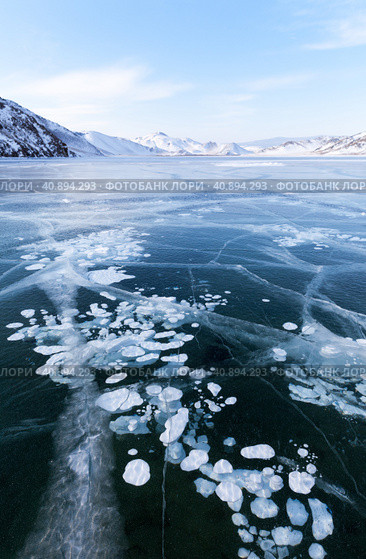 Beautiful winter landscape of frozen Baikal Lake in cold winter day. Blue ice fields with white bubbles and cracks in iced Anga bay. Natural seasonal background. Winter ice travel and active outdoors. Стоковое фото, фотограф Виктория Катьянова / Фотобанк Лори