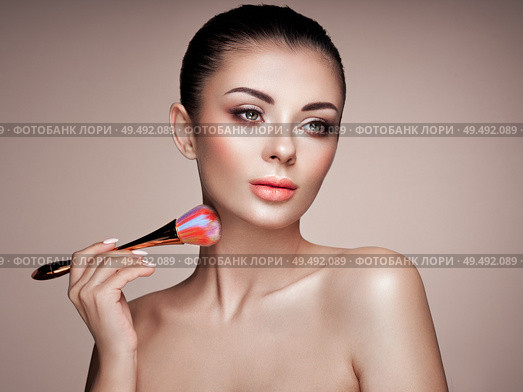 Beautiful Woman applies Skin Tone with Brush. Beautiful Woman face. Perfect Makeup. Skincare Foundation. Brushes Makeup Artist. Стоковое фото, агентство Ingram Publishing / Фотобанк Лори