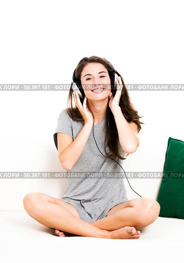Beautiful woman on a sofa and listen music, isolated in white. Стоковое фото, агентство Ingram Publishing / Фотобанк Лори