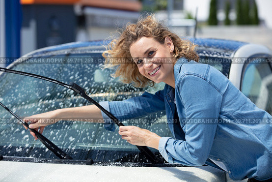 beautiful woman picking up windscreen wiper and checking it. Стоковое фото, агентство Ingram Publishing / Фотобанк Лори