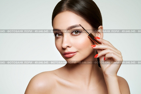 Beautiful woman puts mascara on her eyebrows. Eyelash extensions. Healthy clean fresh skin natural make up beauty eyes. Стоковое фото, агентство Ingram Publishing / Фотобанк Лори