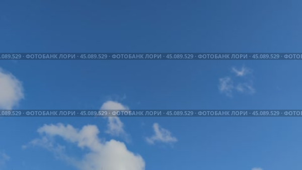 Белые облака летят по небу. На фоне светло голубого неба медленно плывут кучевые облака, они находятся на разной высоте. Сквозь облака видно небо. Облака на ходу меняют свою форму и размер. Стоковое видео, видеограф Andrew_Swarga / Фотобанк Лори