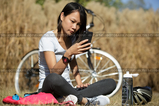 biking cyclist woman using mobile phone texting during workout break. Стоковое фото, агентство Ingram Publishing / Фотобанк Лори