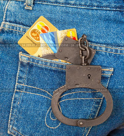 Black metal handcuffs and credit cards in back jeans pocket. Редакционное фото, фотограф FotograFF / Фотобанк Лори