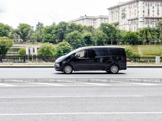 Black passenger van Hyundai Staria in the city street in motion. Luxury korean minivan drive fast. Редакционное фото, фотограф Константин Григорьев / Фотобанк Лори