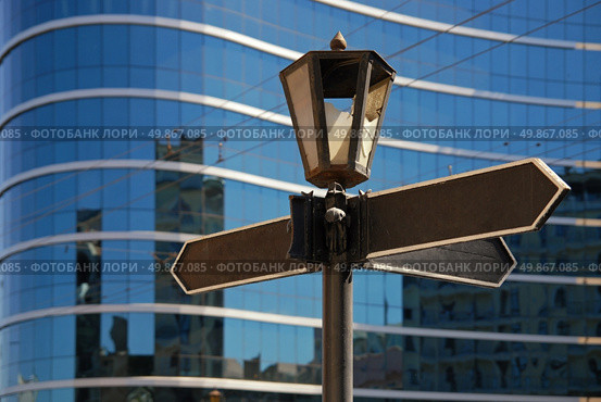 Blank signpost with ancient lamp against business building. Стоковое фото, агентство Ingram Publishing / Фотобанк Лори