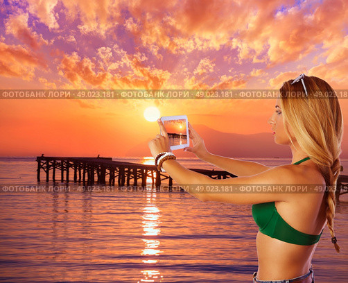 Blond tourist girl taking photos of Mallorca Alcudia beach sunset photomount. Стоковое фото, агентство Ingram Publishing / Фотобанк Лори