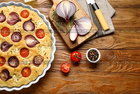 Блюдо для выпечки с вкусной итальянской фокаччей и ингредиентами на деревянном фоне. Стоковое фото, фотограф Pixel_shot / Фотобанк Лори