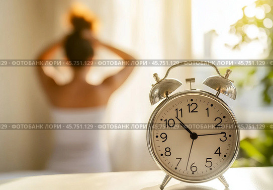 Blurred Woman waking up and stretching her arm, focus on the alarm clock at 10 o'clock in the morning. Closeup vintage retro style alarm clock, young Asian girl wake up sitting on bed. Hello, new day. Стоковое AI-изображение, AI-художник Марина Демидюк / Фотобанк Лори