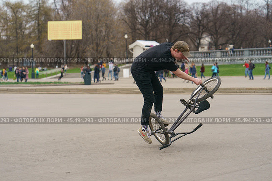 BMX in the Moscow park. Young man doing trick on the bike in the spring day. Extreme sports is very popular among youth. 2019. Редакционное фото, фотограф YuryKara / Фотобанк Лори
