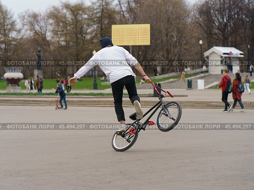 BMX in the Moscow park. Young man doing trick on the bike in the spring day. Extreme sports is very popular among youth. 2019. Стоковое фото, фотограф YuryKara / Фотобанк Лори