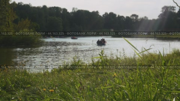 Boats with vacationing people float on the surface of the park pond. Russia. Moscow. Kuzminki Park. 17.08.2024. Редакционное видео, видеограф Ярославский Максим / Фотобанк Лори