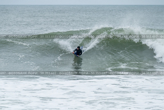 Bodyboarder surfing ocean wave on a cloudy winter day. Стоковое фото, агентство Ingram Publishing / Фотобанк Лори