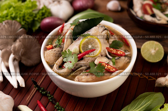Boil the fish infusion with tomatoes, mushrooms, coriander, spring onion and lemongrass in a bowl. Стоковое фото, агентство Ingram Publishing / Фотобанк Лори