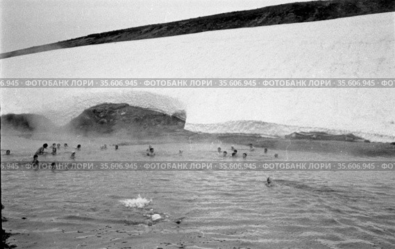 Большое количество детей школьного возраста купаются в ледяном водоёме, люди плавают рядом с ледником, пар поднимается из реки в воздух, Чукотка, 1970 год. Редакционное фото, фотограф Варфоломей Тетерин / Фотобанк Лори