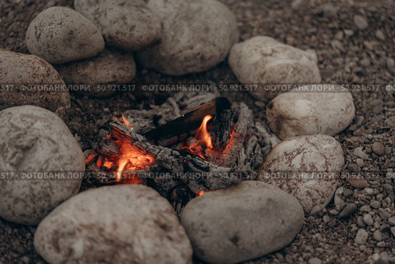 Bonfire on a pebble beach. Smoldering coals in a fire pit. Стоковое фото, фотограф София Тюленева / Фотобанк Лори