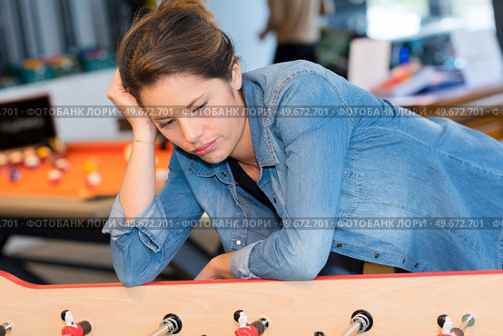 bored woman alone while husband is playing table football. Стоковое фото, агентство Ingram Publishing / Фотобанк Лори