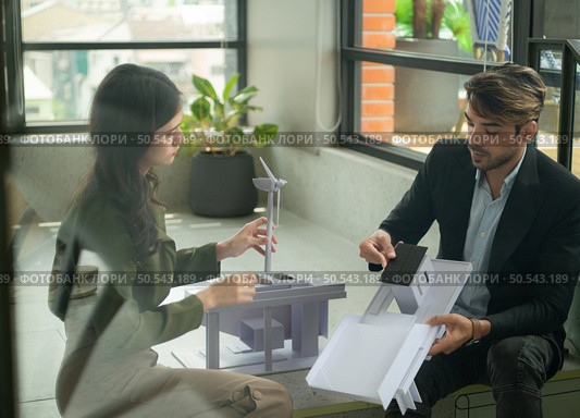 Both of businessperson sitting on stairs in office talk and exchange ideas on using natural energy in buildings before entering the meeting to present and consider. Стоковое фото, агентство Ingram Publishing / Фотобанк Лори