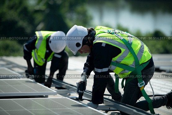 Both of Engineer in charge of solar panel installation The installation of solar energy conversion into electricity for a warehouse is currently being investigated. Стоковое фото, агентство Ingram Publishing / Фотобанк Лори