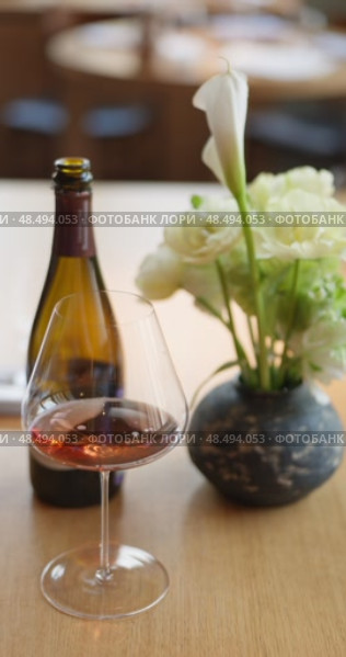 bottle of rose champagne is on table, flowers, wine glass in the restaurant, local lighting, wine cabinet, decanters for sparkling wine. Стоковое видео, видеограф Vladimir Drozdin / Фотобанк Лори