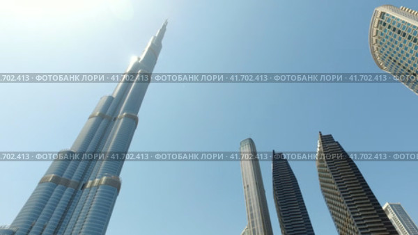 Bottom view of skyscrapers of Dubai city, UAE with Burj Khalifa at blue sky. Panorama urban cityscape of new towers. Construction and architecture concept (2023 год). Редакционное видео, видеограф Aleksandr Golubev / Фотобанк Лори