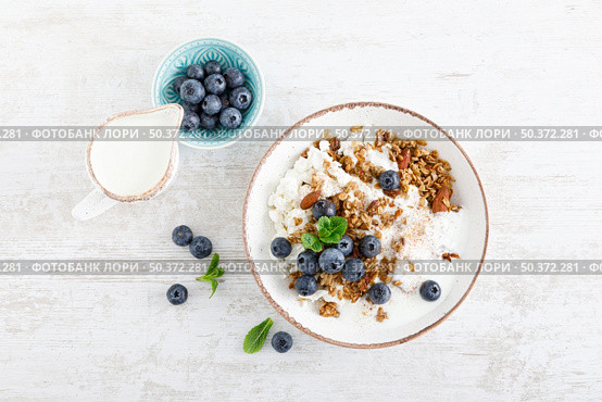 Bowl of granola with fresh blueberry, cottage cheese or curd, yogurt and nuts. Healthy food. Breakfast. Top view. Стоковое фото, агентство Ingram Publishing / Фотобанк Лори