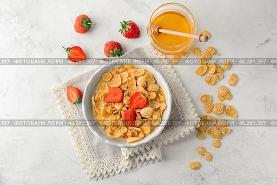 Bowl with healthy cornflakes, honey and strawberry on white table. Стоковое фото, фотограф Pixel_shot / Фотобанк Лори