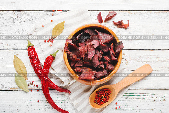 Bowl with spicy beef jerky on white wooden background. Стоковое фото, фотограф Pixel_shot / Фотобанк Лори