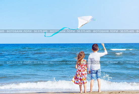 Boy and girl at the beach with a kite. Freedom concept. Carefree childhood and hope. Brother and sister together. Стоковое фото, агентство Ingram Publishing / Фотобанк Лори