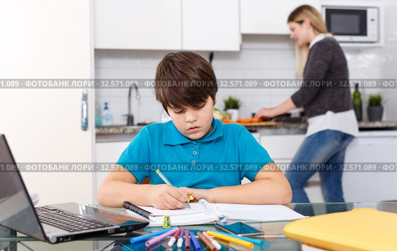 Boy doing homework, mother cooking. Стоковое фото, фотограф Яков Филимонов / Фотобанк Лори