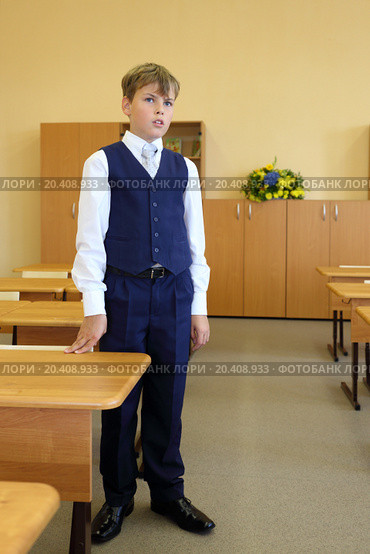Boy stands next to desk in classroom and answer teacher question in school. Стоковое фото, фотограф Losevsky Pavel / Фотобанк Лори