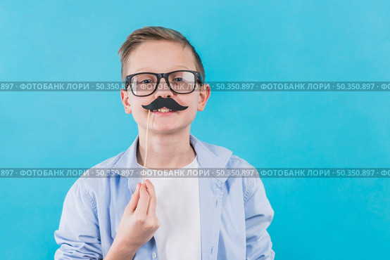 boy wearing black eyeglasses holding black moustache prop front his upper lips. Стоковое фото, агентство Ingram Publishing / Фотобанк Лори
